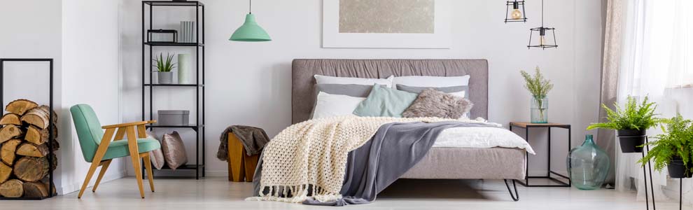 cozy bedroom with plants, knit blankets and throw pillows